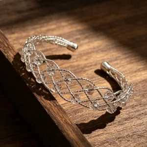 Primo piano del bracciale rigido in argento intrecciato con perle di cristallo scintillanti.