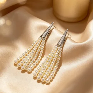 Close-up of elegant pearl tassel earrings, featuring multi-strand white pearls and sparkling rhinestone accent.
