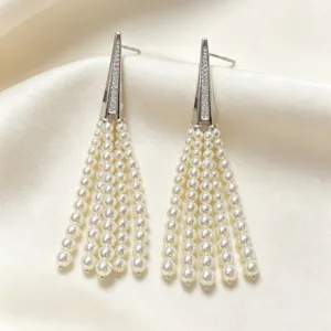 Close-up detail of elegant long silver tassel earrings with white pearls and sparkling crystals.