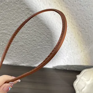 Serre-tête fin en cuir PU marron minimaliste, détail de coutures fines et chic style.