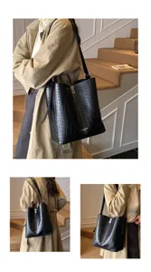 Vue détaillée du sac seau noir en motif crocodile élégant porté par le mannequin.