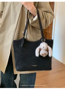 Vue détaillée d'un sac cabas en cuir noir avec coutures blanches, bandoulière et charm lapin.