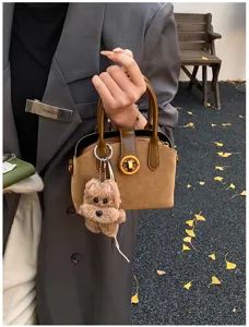 Chic retro brown suede handbag for women, elegant top handle bag with cute plush bear charm.