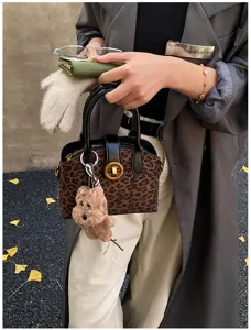 Chic leopard print women handbag featuring top handle, metal lock and cute plush puppy charm.