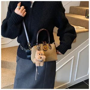 Detailed close-up view of the stylish brown shoulder bag featuring a fluffy pendant and lock.
