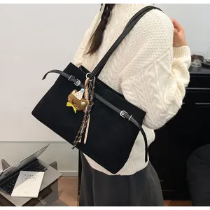 Detailed view of women's black suede shoulder tote bag with cute bear charm and belt accent.