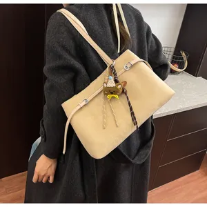 Chic winter suede shoulder bag detail, elegant khaki tone with cute bear charm accent.