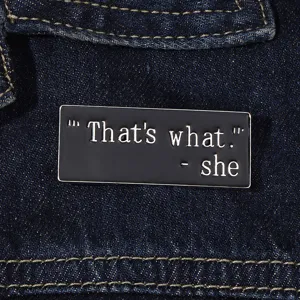 Minimalist metal enamel badge with quote design, sleek black finish for apparel decor.