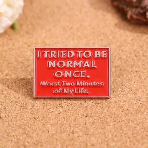 Close-up detail van een rode metalen broche met gegraveerde Engelse tekst, tasdecoratie.