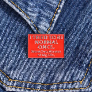 Close-up detail van rode rechthoekige emaille metalen speld badge met grappig citaat.