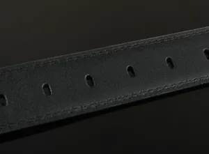 Close-up view of premium black leather belt strap featuring neat double stitching and holes.