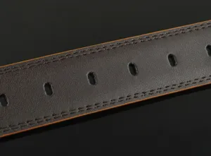 Close-up detail of dark brown leather belt, showing exquisite double stitching and belt holes.