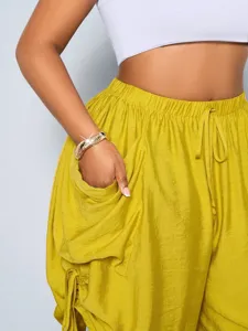 High-waist harem pants detail showing loose fit, drawstring waist and side pockets.