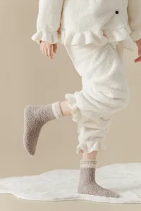 Cozy fuzzy sleep socks detail, soft coral fleece texture, warm home floor socks for winter.