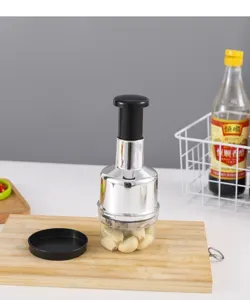 Detail shot of manual stainless steel garlic press with transparent container and black handle.