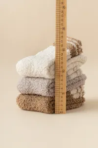 Detail view of cozy coral fleece sleeping socks stacked neatly with a measuring ruler.