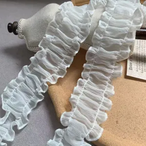 Detail shot of white pleated organza lace trim, delicate ruffle design for doll clothes DIY crafting.