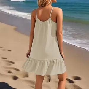 Achteraanzicht van een casual beige strandjurk met een stijlvolle volantzoom op het zand.