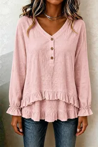 Detailed view of the pink long-sleeve blouse featuring ruffled hem and wooden buttons.