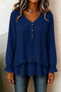 Detail view of dark blue long sleeve top, featuring ruffled hem and wooden buttons.