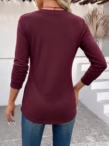 Back view detail of a stylish burgundy long sleeve top paired with blue jeans in a modern setting.