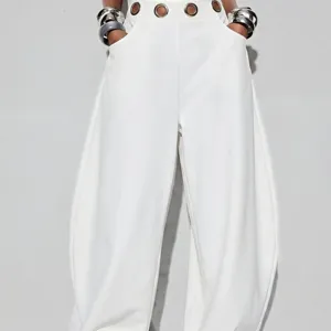 Pantalon sarouel blanc ample pour femmes avec œillets métalliques. Mode élégante.