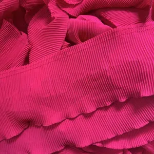 Close-up of bright pink pleated chiffon lace fabric trim, showing fine texture and neat stitching.