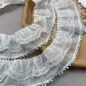 Close-up detail of double layer white chiffon lace trim with pearl fringe for DIY decoration.