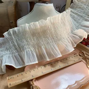 Close-up detail of beige elastic chiffon ruffle trim, perfect for sewing and DIY crafts.