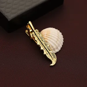 Dettaglio fermacravatta a piuma dorata, elegante accessorio in metallo per abiti.