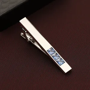 Gros plan d'une pince a cravate pour homme en argent ornee de trois cristaux bleus carres.