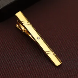 Detail view of a gold men's tie clip featuring a sparkling crystal accent and sleek striped lines.