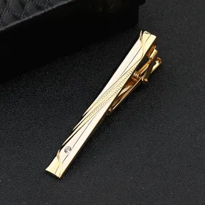 Nahaufnahme einer goldenen Krawattenklammer mit Gravur und Kristall für Herrenanzüge.