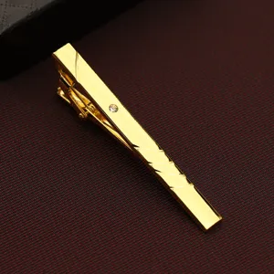 Close-up detail shot of a sleek golden men's business tie clip featuring a delicate crystal inlay.