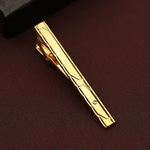 Detail view of a stylish gold tie clip with geometric engraved patterns for modern men