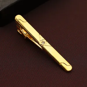 Gold tone metal tie clip for men detail view, featuring clear crystal accent and geometric lines.
