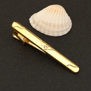 Vista detallada de pinza de corbata de metal dorado con brillante adorno de estrás fin.