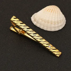 Primer plano de un elegante sujetacorbatas dorado con texturas diagonales y un brillante.