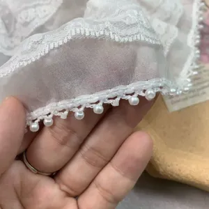 White chiffon pearl lace trim close-up view, delicate DIY sewing accessory detail presentation.