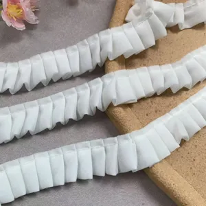 Nahaufnahme von weißer doppelten Chiffon-Spitzenborte, zeigt Textur und geraffte Falten.