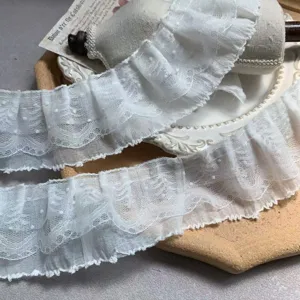 Detailed close-up of white 3-layer dotted lace ruffle trim, delicate mesh DIY craft fabric.