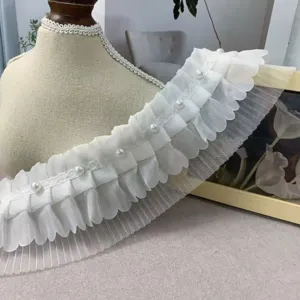 Close-up of 8cm white pleated tulle lace trim with pearl beading for apparel and crafts.