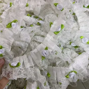 Gros plan de détail d'une bordure en dentelle organza blanche de 5 cm avec des mini roses.