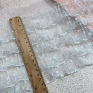 Close-up view of white polka dot mesh ruffled lace trim fabric detail for DIY sewing projects.