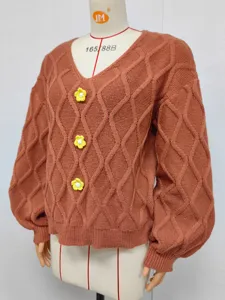Detailansicht des braunen V-Ausschnitt Strickpullovers mit Rautenmuster und gelben Häkelblumen.