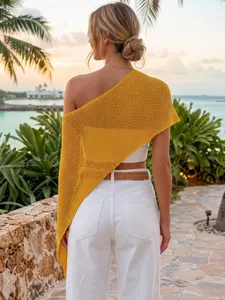 Vista detallada del top capa asimétrico de punto calado amarillo para las vacaciones en la playa.