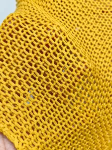 Primer plano del tejido de chal de punto calado amarillo con diseño de malla fina.