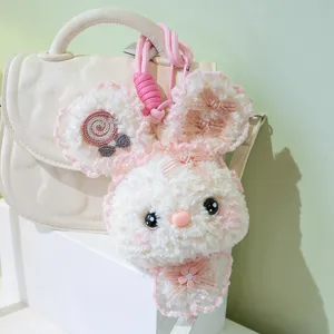 Detail shot of cute plush rabbit bag charm with pink bow and lollipop decor, soft toy pendant.