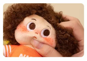 Close-up detail of cute afro curly hair plush doll face with embroidery eyes and soft texture.