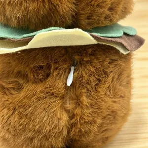 Brown plush toy doll detail view soft furry fabric with back zipper and burger collar design